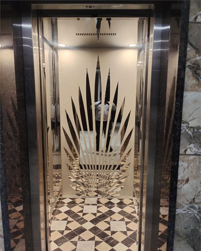 A lift cabin with an etched mirror back panel above a black and white chequered floor