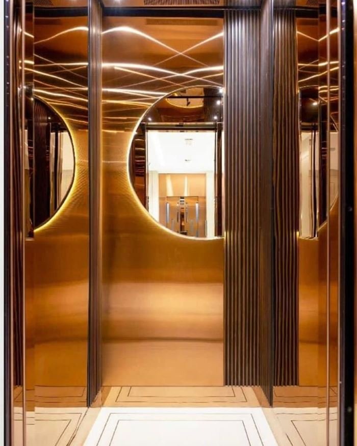 A bronze lift cabin with an arched cut-out feature panel and warm cove lighting