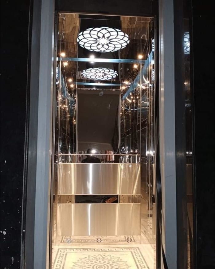 A dark lift cabin with a decorative crystal-style ceiling and full mirror walls