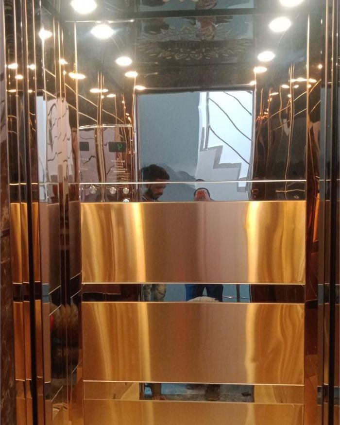 A rose gold lift cabin with banded horizontal wall panels
