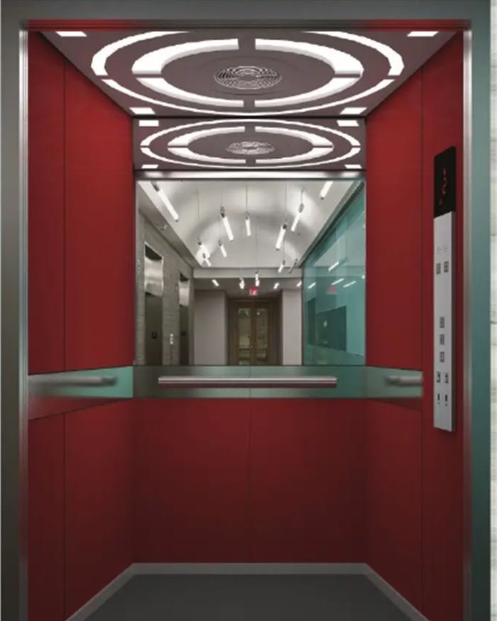 A red panelled lift cabin with an oval patterned ceiling and mirror side walls