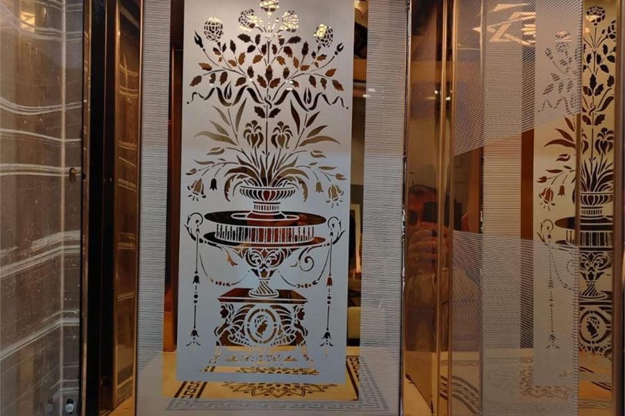 An etched mirror-steel cabin panel with a marble inlay floor below it